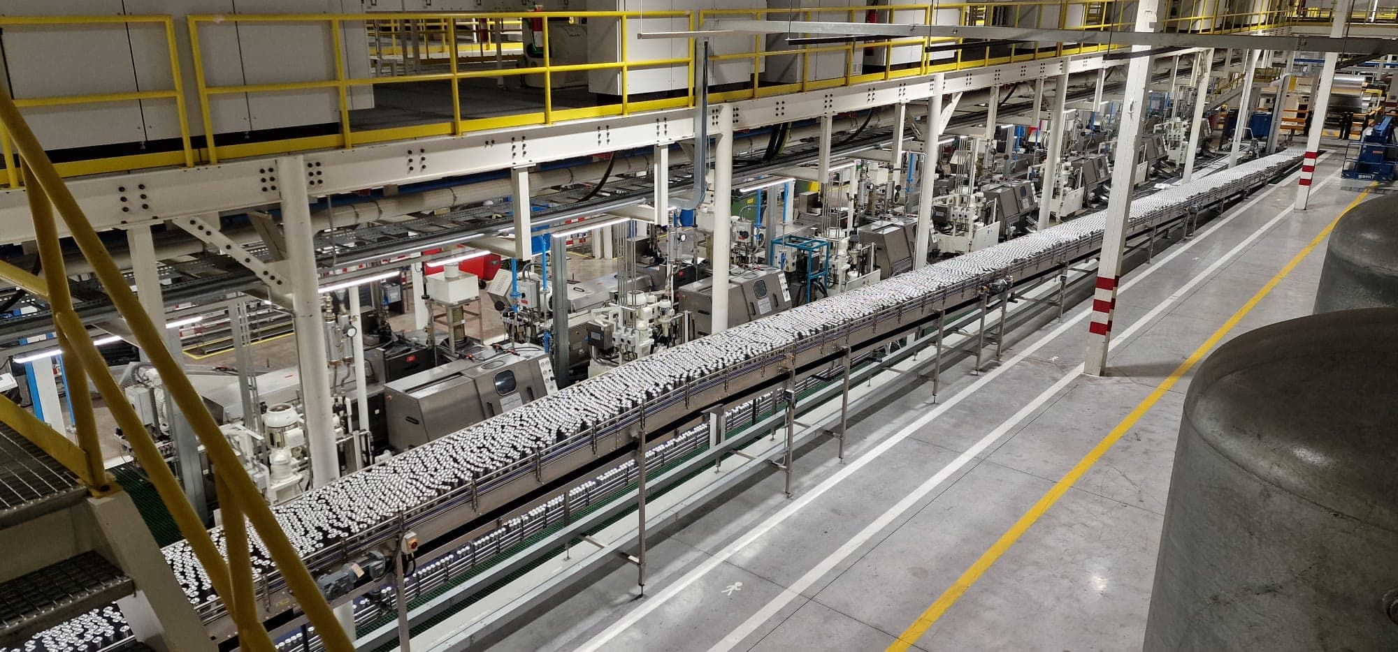 Long single-file can conveyor running above the machine hall