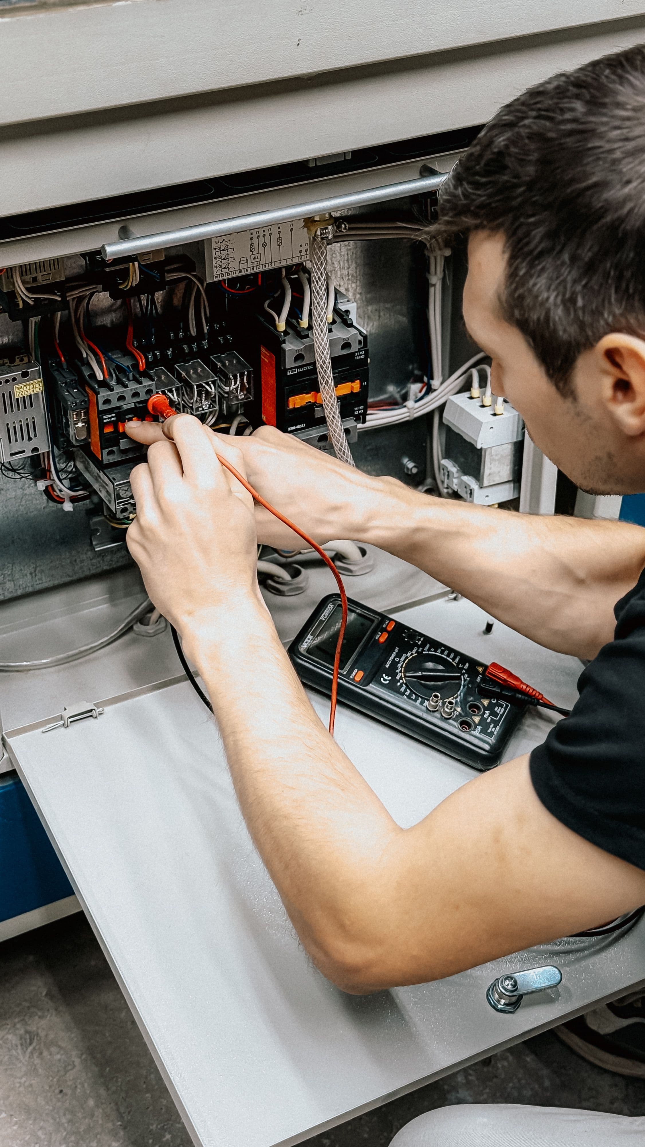 Engineer taking a reading inside a control panel with a multimeter