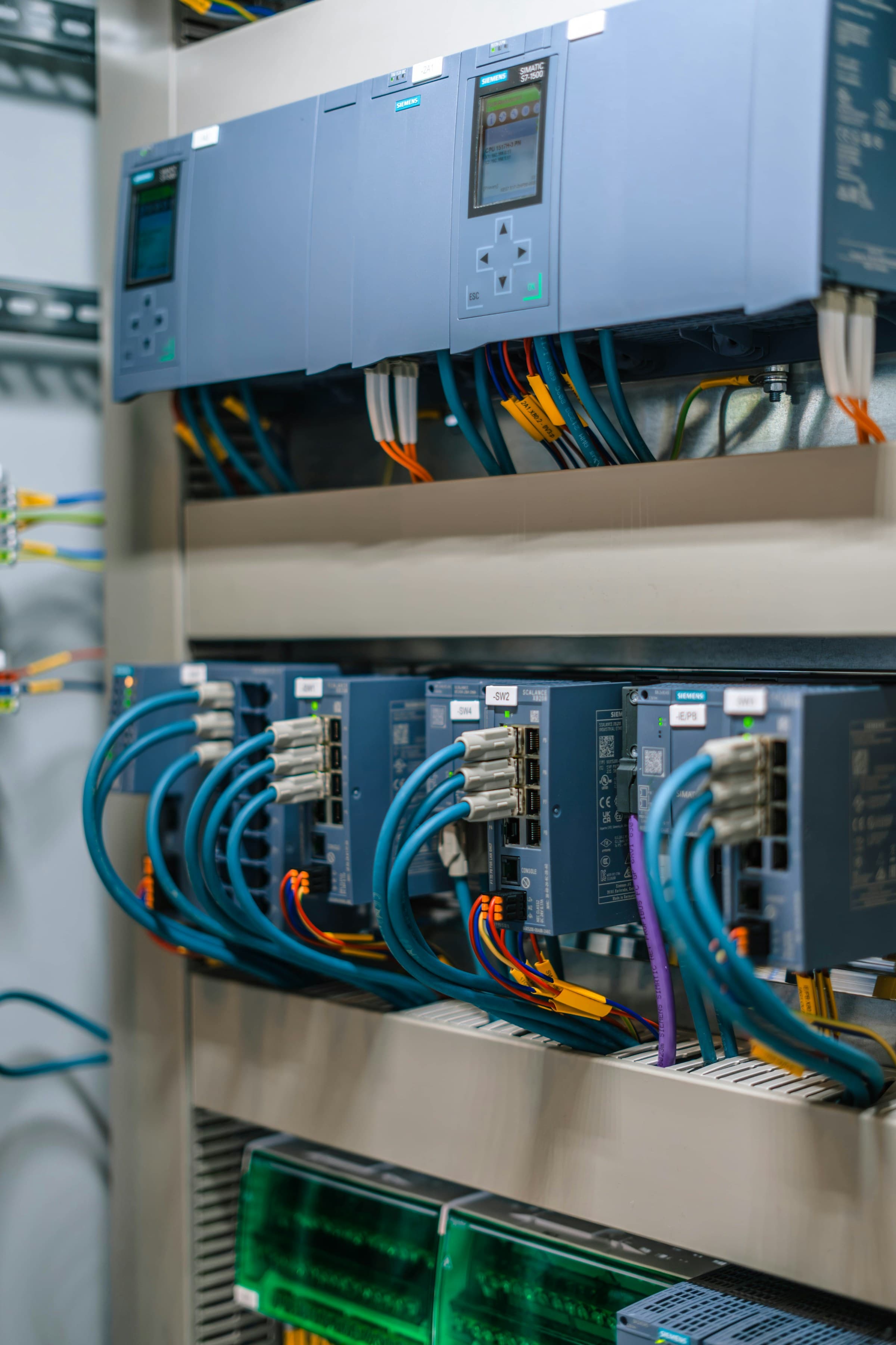 Network and control modules linked with blue cabling inside a control panel