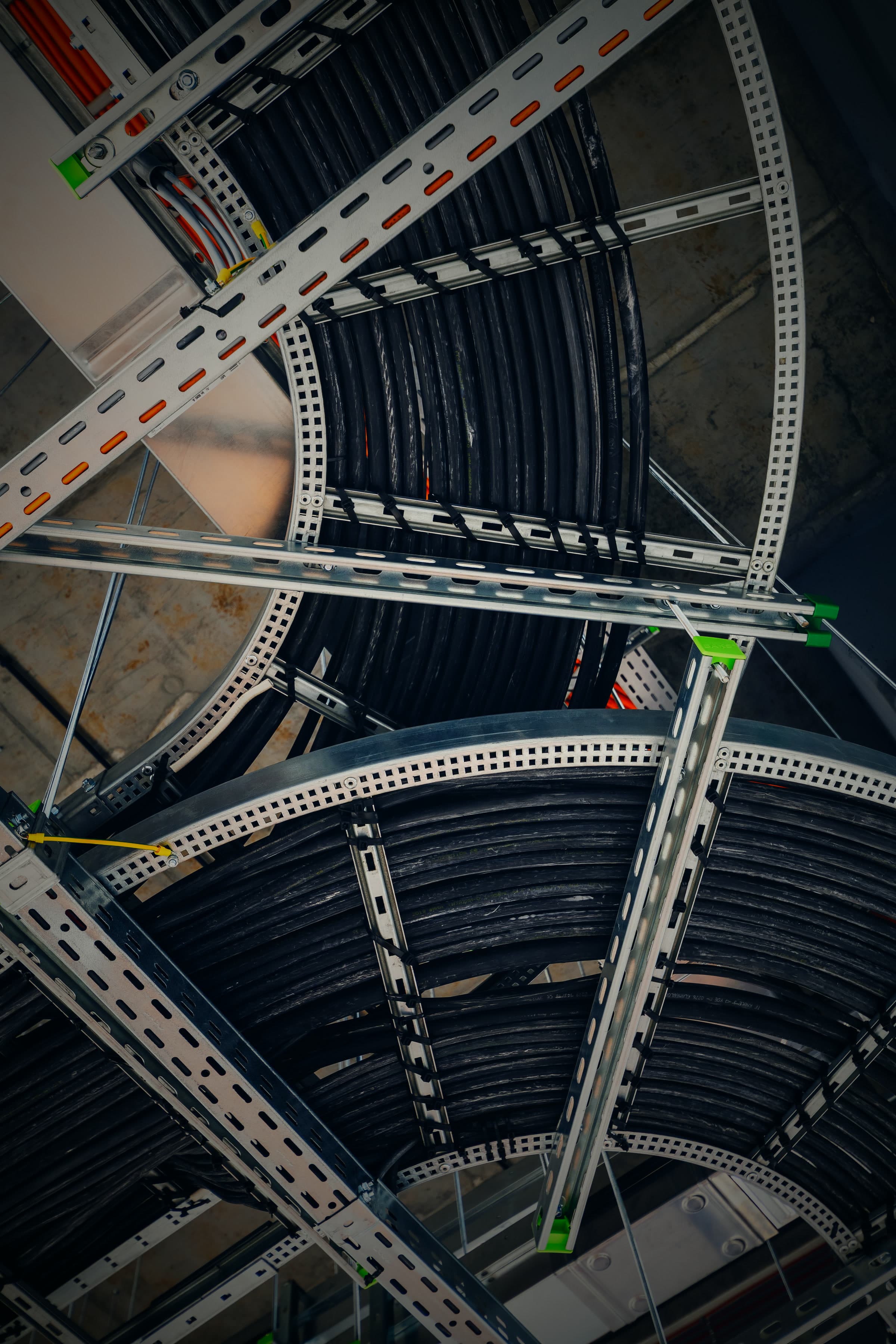 Looking up at curved cable ladders carrying dressed and tied power cables