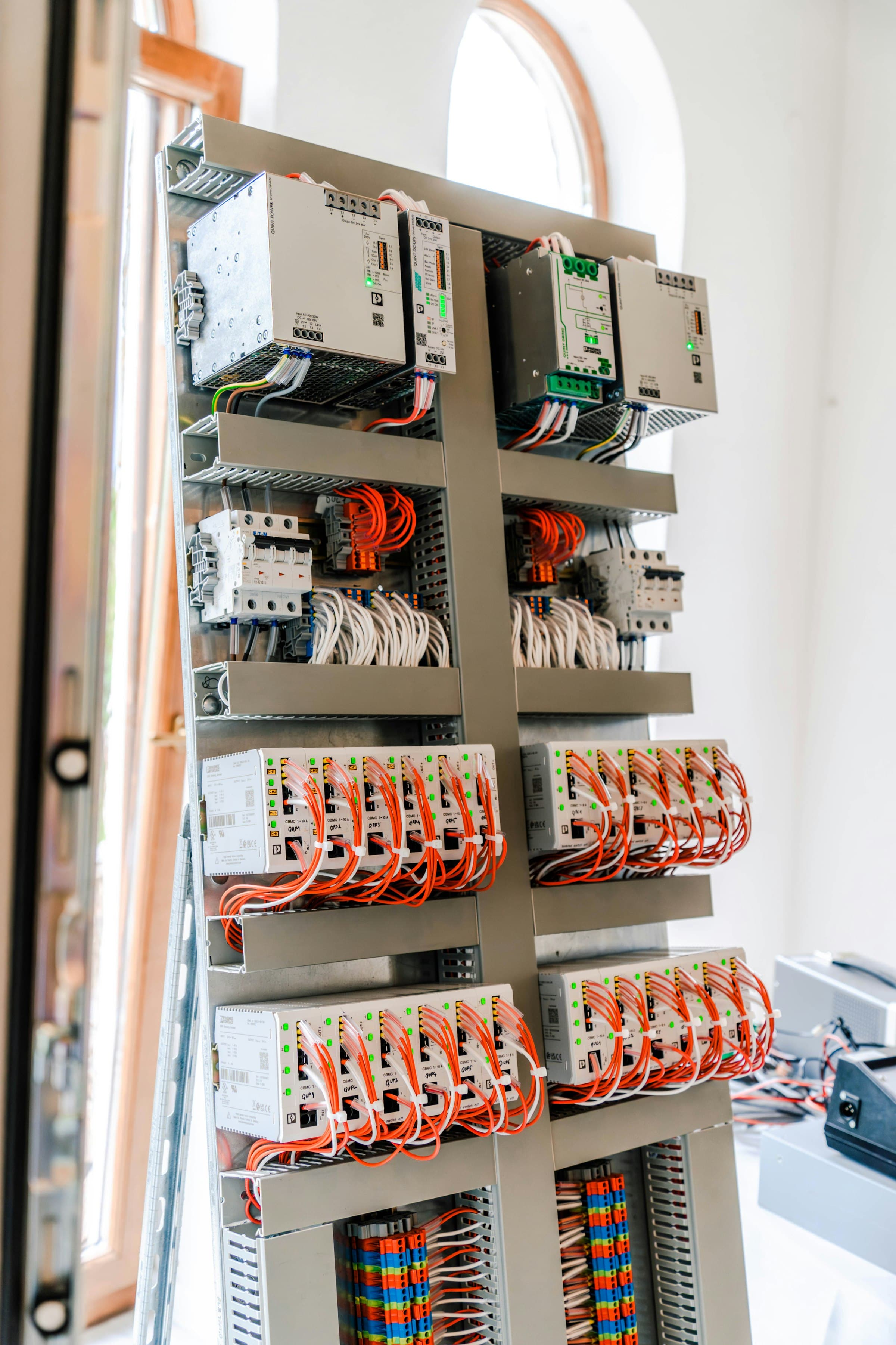 Open control panel with DIN-rail breakers and neatly combed orange wiring
